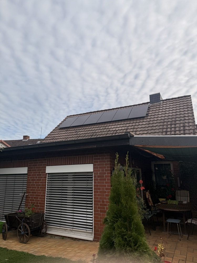 Das Haus von der Gartenseite mit PV-Modulen auf dem Dach