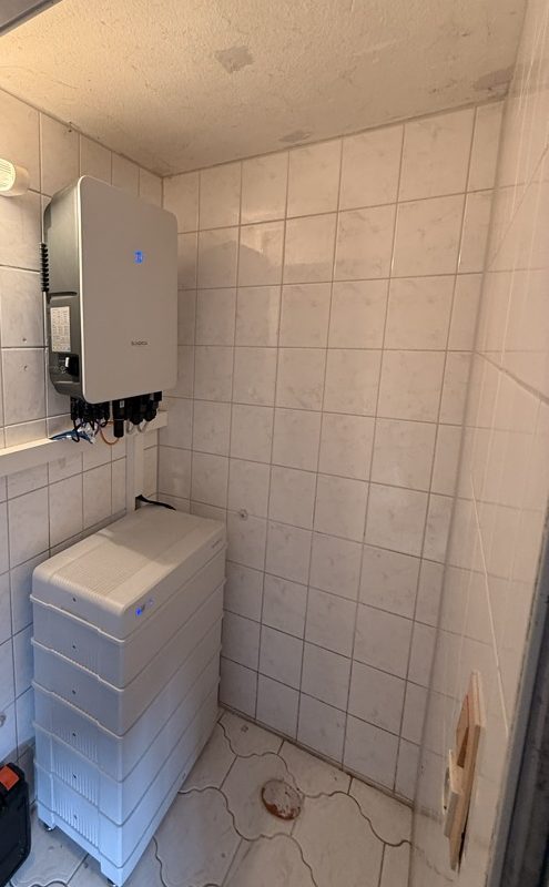 Sungrow-Wechselrichter an der Wand und der 16-kWh-Speicherturm im gefliesten Technikraum